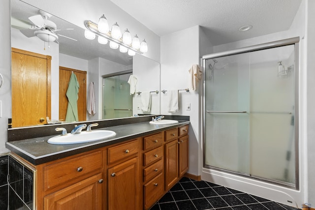 bathroom with ceiling fan, tile patterned flooring, vanity, a textured ceiling, and a shower with shower door