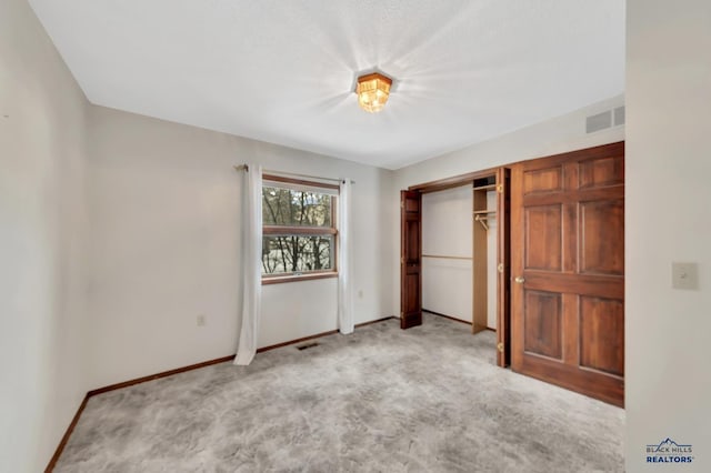 unfurnished bedroom featuring light colored carpet and a closet