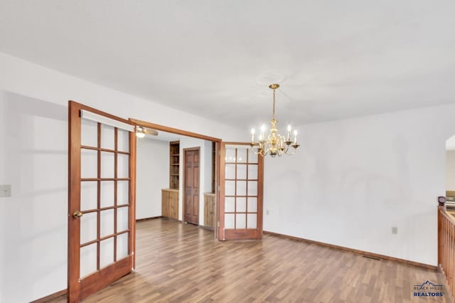 spare room featuring hardwood / wood-style floors, a chandelier, and french doors