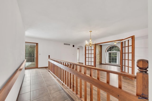 hall featuring a notable chandelier and light tile patterned flooring