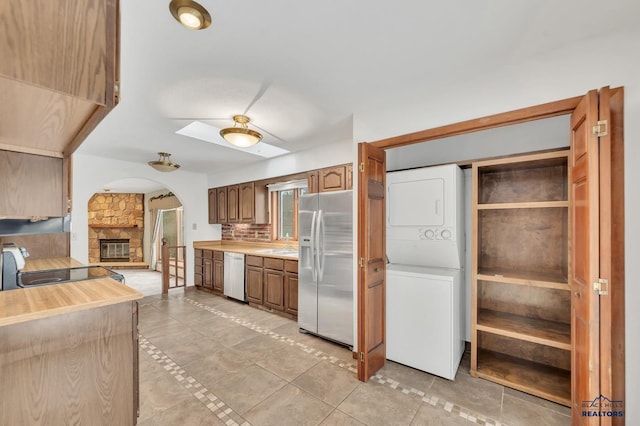 kitchen featuring stacked washer / dryer, appliances with stainless steel finishes, and a fireplace