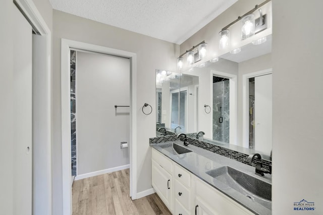 bathroom with walk in shower, vanity, hardwood / wood-style floors, and a textured ceiling