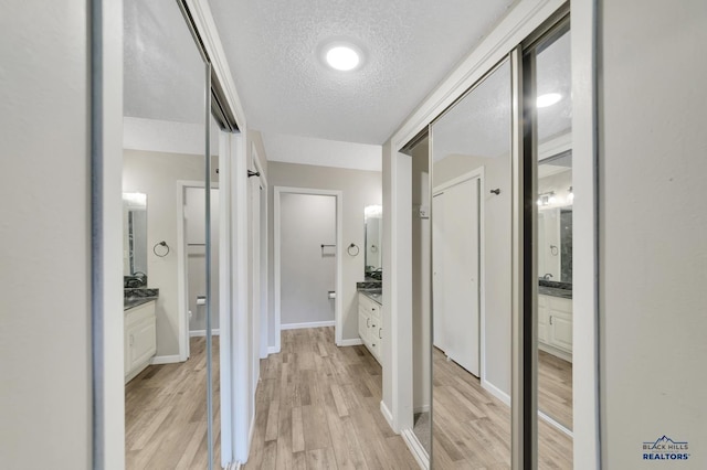 hall with a textured ceiling and light wood-type flooring