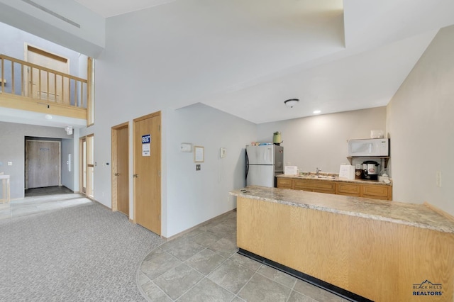 kitchen with sink, light carpet, and stainless steel fridge