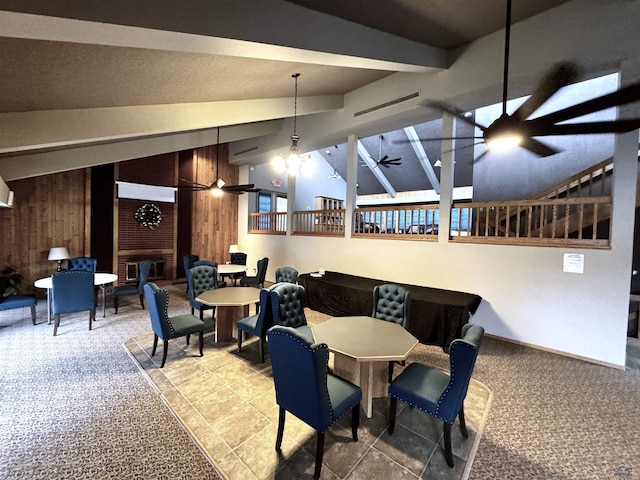 carpeted dining room featuring lofted ceiling, ceiling fan, and wood walls