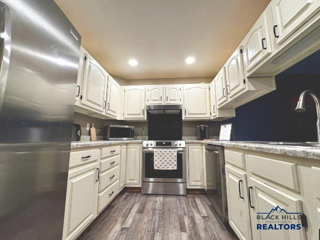 kitchen with stainless steel appliances, dark hardwood / wood-style floors, sink, and white cabinets