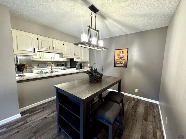 kitchen featuring white cabinetry, decorative light fixtures, stainless steel appliances, and kitchen peninsula