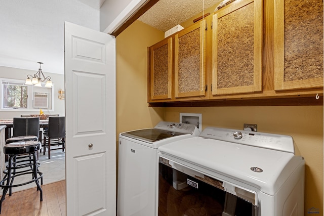 laundry room featuring cabinets, separate washer and dryer, an inviting chandelier, and light hardwood / wood-style flooring