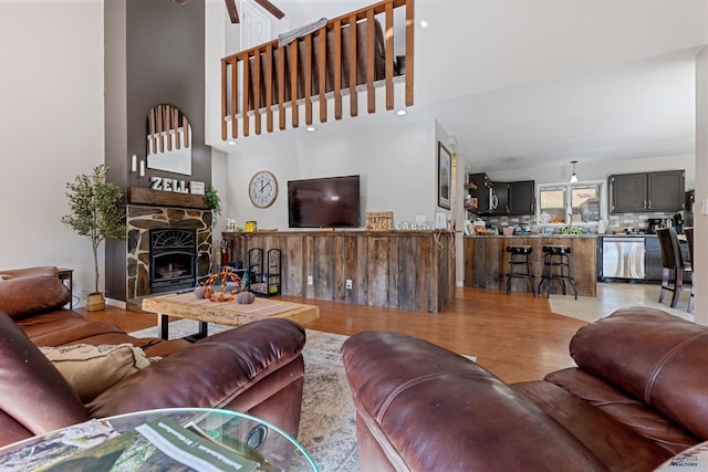 living room with light wood-type flooring, a fireplace, and a towering ceiling