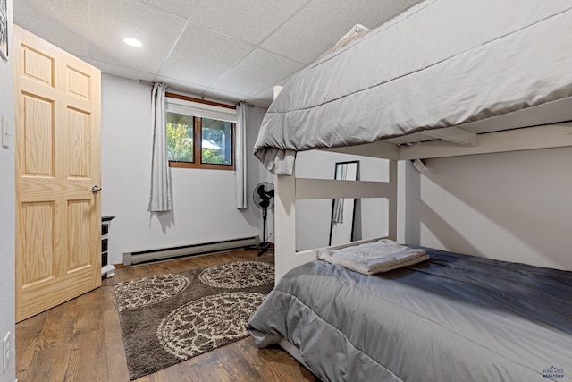 bedroom featuring baseboard heating, a paneled ceiling, and dark hardwood / wood-style flooring