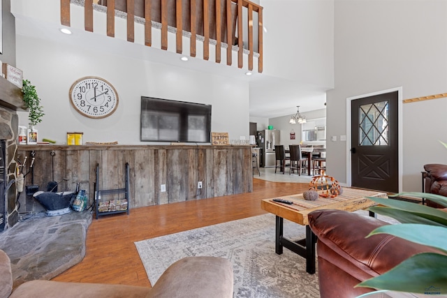 living room with a high ceiling, wood-type flooring, and an inviting chandelier