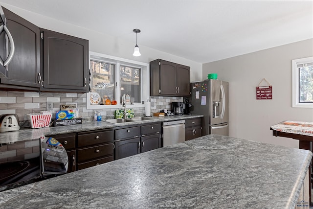 kitchen with pendant lighting, sink, appliances with stainless steel finishes, backsplash, and dark brown cabinets