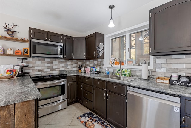 kitchen featuring light tile patterned flooring, sink, decorative light fixtures, dark brown cabinets, and appliances with stainless steel finishes