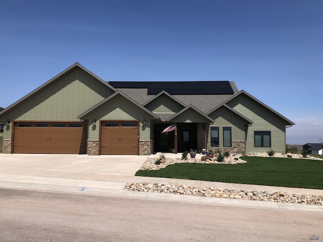 craftsman-style house featuring a garage, a front lawn, and solar panels