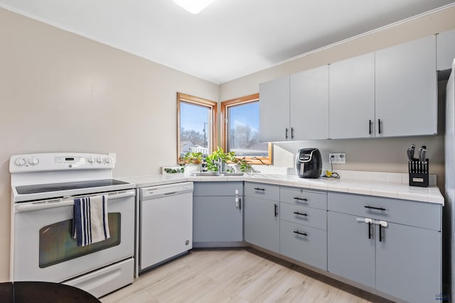 kitchen featuring gray cabinets, sink, white appliances, and light wood-type flooring