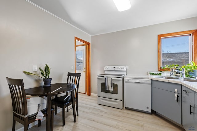 kitchen with sink, white appliances, gray cabinets, and light wood-type flooring