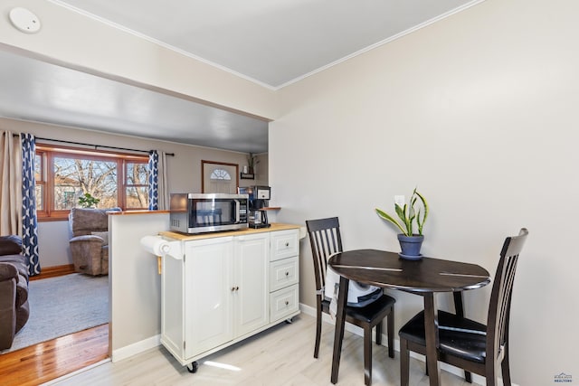 dining space with light hardwood / wood-style flooring and ornamental molding