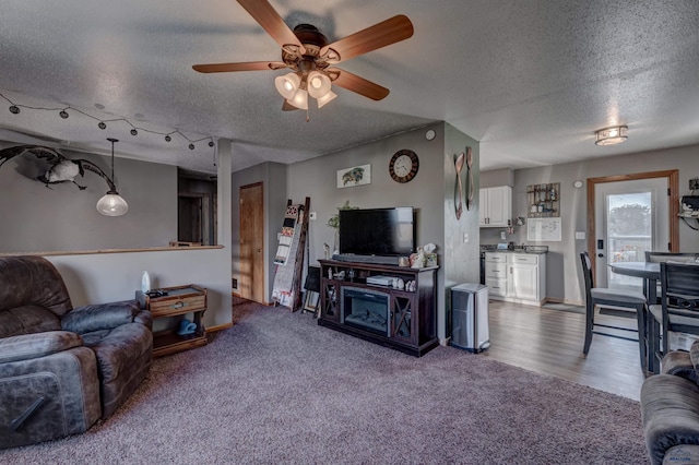 living room featuring ceiling fan, carpet floors, and a textured ceiling