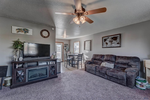 living room with ceiling fan, carpet, and a textured ceiling