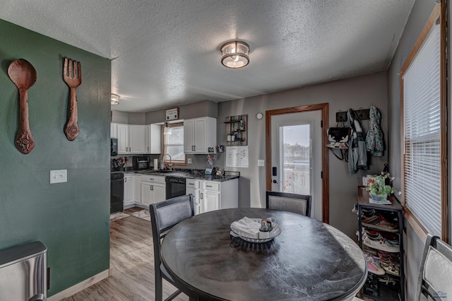 dining space with light hardwood / wood-style floors, sink, and a textured ceiling