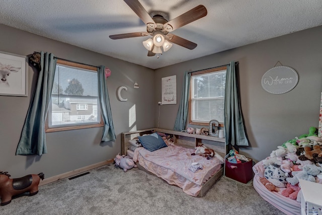 carpeted bedroom featuring ceiling fan and a textured ceiling