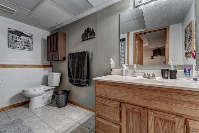 bathroom featuring vanity, toilet, tile patterned flooring, and a drop ceiling