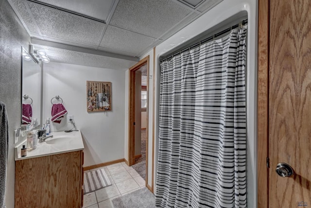 bathroom with vanity, a drop ceiling, and tile patterned floors