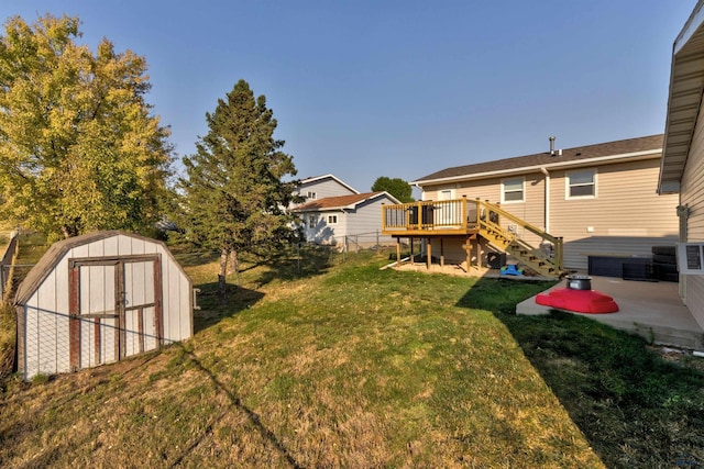 view of yard with a wooden deck, a storage unit, and a patio area