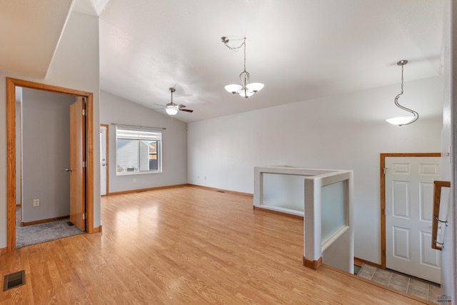 unfurnished living room with lofted ceiling, ceiling fan with notable chandelier, and light wood-type flooring