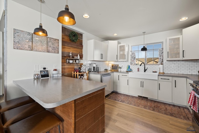 kitchen featuring pendant lighting, a breakfast bar area, kitchen peninsula, and white cabinets