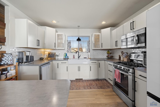 kitchen with pendant lighting, appliances with stainless steel finishes, sink, and white cabinets