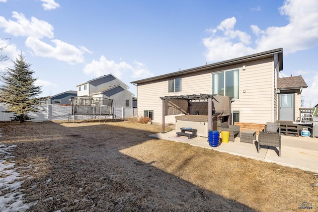 back of property featuring a trampoline, a pergola, a hot tub, and a patio