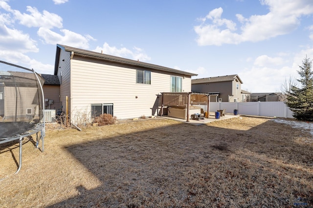 rear view of house featuring a trampoline, a jacuzzi, and a patio