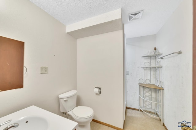 bathroom featuring sink, a textured ceiling, and toilet