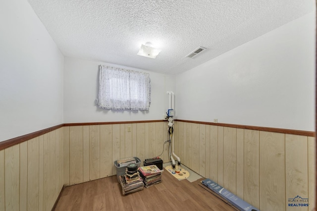 workout room with a textured ceiling and light wood-type flooring