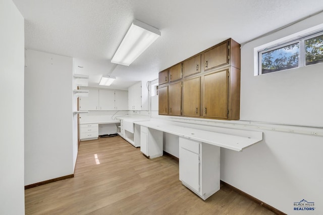 interior space with built in desk, a textured ceiling, and light hardwood / wood-style floors