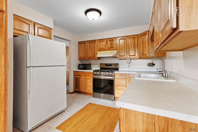 kitchen with sink, gas range, a textured ceiling, and white fridge