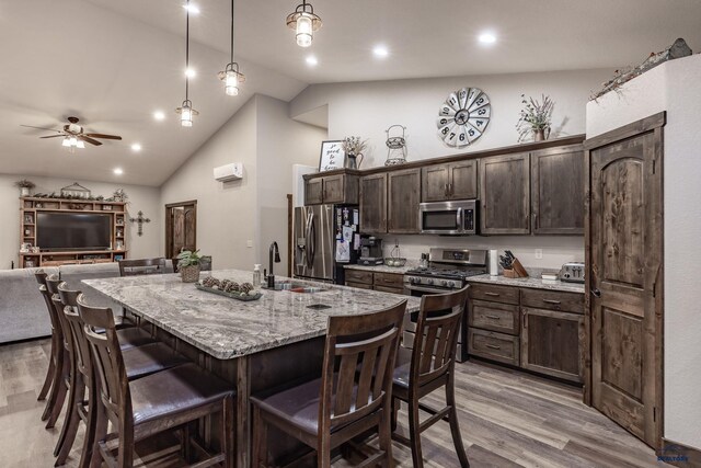 23232 Clear Creek Rd, Rapid City, SD 57702 - kitchen featuring decorative light fixtures, an island with sink, dark brown cabinetry, light hardwood / wood-style floors, and stainless steel appliances