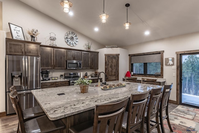 23232 Clear Creek Rd, Rapid City, SD 57702 - kitchen featuring lofted ceiling, sink, appliances with stainless steel finishes, hanging light fixtures, and a center island with sink