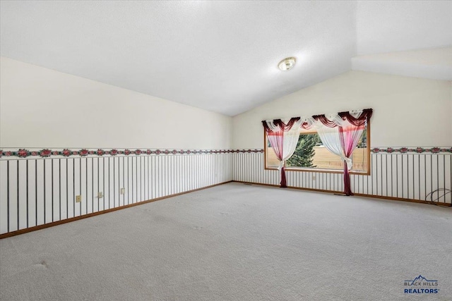 carpeted empty room featuring lofted ceiling