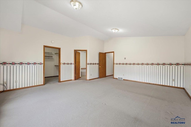 empty room featuring vaulted ceiling and carpet flooring