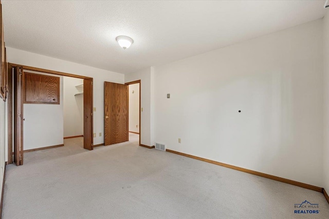 unfurnished bedroom featuring light carpet, a closet, and a textured ceiling