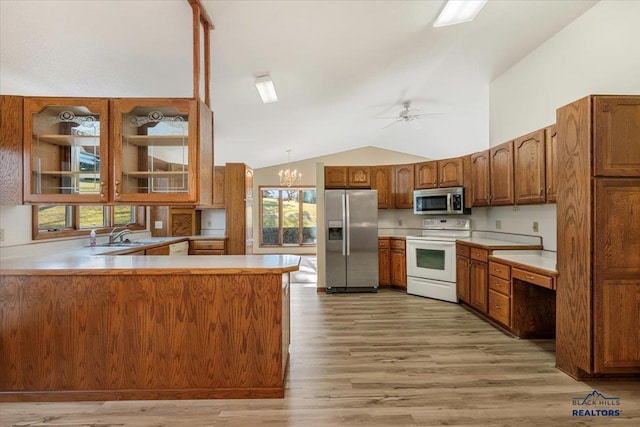 kitchen featuring vaulted ceiling, ceiling fan with notable chandelier, hanging light fixtures, kitchen peninsula, and stainless steel appliances