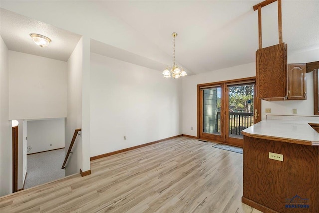 kitchen featuring lofted ceiling, decorative light fixtures, a chandelier, and light wood-type flooring