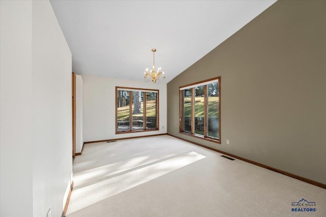 carpeted spare room with high vaulted ceiling and a chandelier