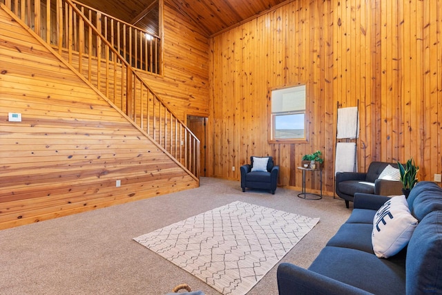 unfurnished living room featuring wood ceiling, a high ceiling, carpet, and wood walls