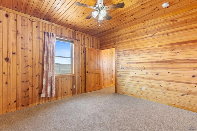 carpeted spare room with wood ceiling, ceiling fan, and wood walls