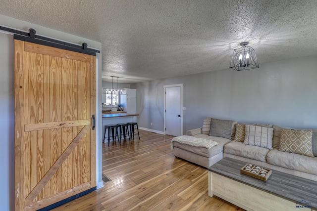 unfurnished living room with hardwood / wood-style flooring, a barn door, a textured ceiling, and an inviting chandelier