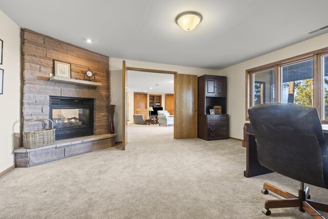 carpeted office space with a stone fireplace