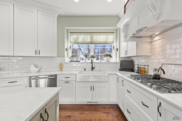 kitchen with appliances with stainless steel finishes, sink, white cabinets, custom exhaust hood, and light stone counters